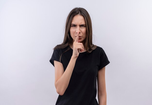 young caucasian girl wearing black t-shirt showing silence gesture on isolated white wall