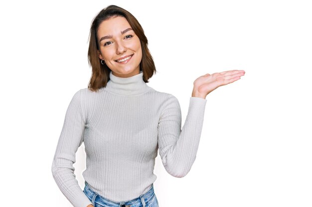 Young caucasian girl wearing casual clothes smiling cheerful presenting and pointing with palm of hand looking at the camera.