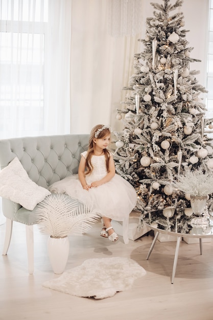 Young caucasian girl in white dress poses for the camera in christmas atmosphere