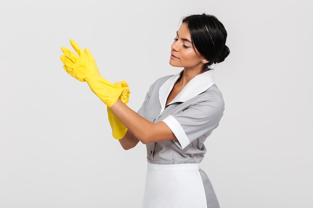 Young caucasian housekeeper wearing protective cleaning gloves, looking aside