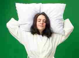 Free photo young caucasian ill girl wearing robe holding pillow under head pretend sleeping isolated on green background