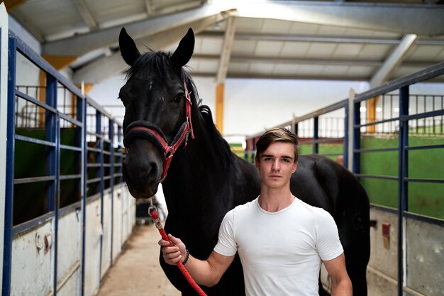 Young Caucasian male posing with his horse before a riding class