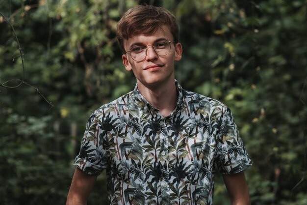 Free photo young caucasian male with eyeglasses posing in a garden