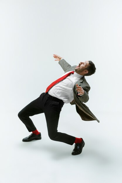 Young caucasian man moving flexible on white wall