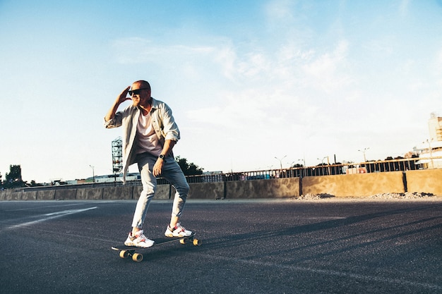 Молодой кавказский человек, езда на лонгборде или скейтборде, современный выстрел в эффект зерна пленки и винтажном стиле.