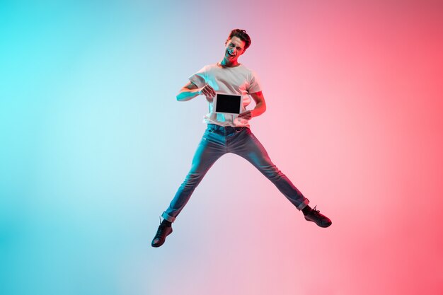 Young caucasian man's portrait on gradient blue-pink in neon light