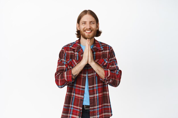 Young caucasian man smiling, showing namaste, thankful gesture, standing over white background