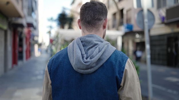 Free photo young caucasian man standing backwards at street