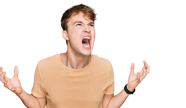 Young caucasian man wearing casual clothes crazy and mad shouting and yelling with aggressive expression and arms raised. frustration concept.