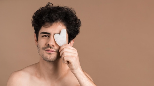 A young caucasian man with stubble beard is posing with Gua Sha