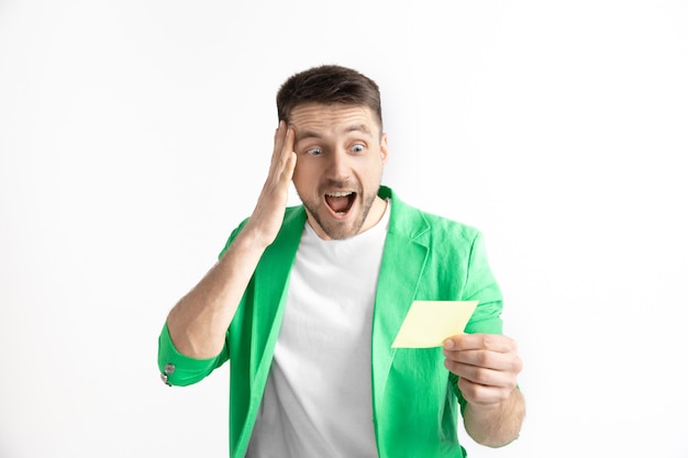 Free photo young caucasian man with a surprised happy expression won a bet on gray studio background. human facial emotions and betting concept