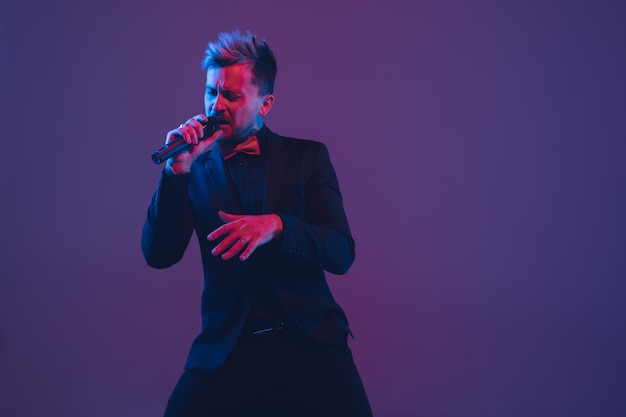 Free photo young caucasian musician singing, dancing in neon light