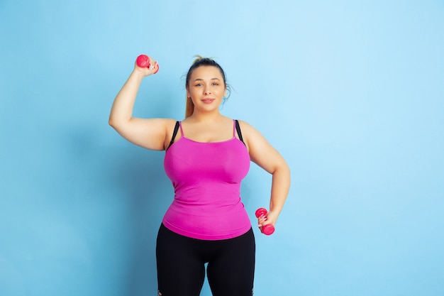 Young caucasian plus size female model's training on blue space