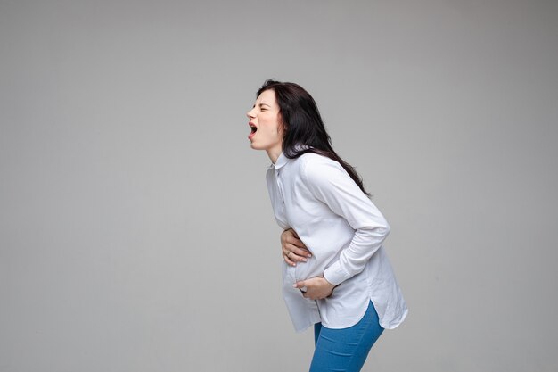 검은 머리가 비명을 지르고 아기를 낳는 젊은 백인 임신 여성