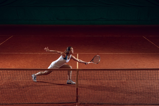 Young caucasian professional sportswoman playing tennis on sport court wall.