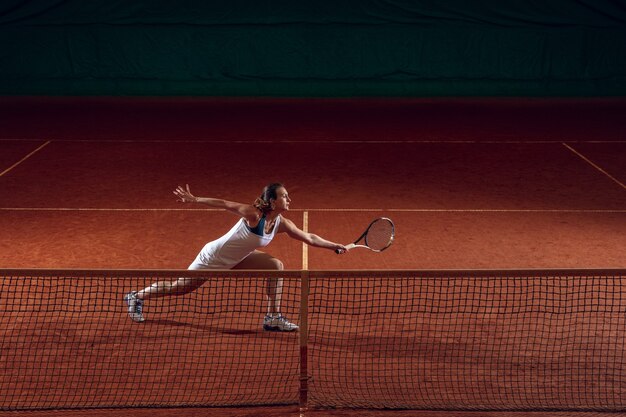 스포츠 코트 벽에서 테니스를 치는 젊은 백인 프로 스포츠우먼.