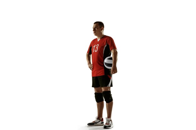 Young caucasian volleyball player placticing on white wall. Male sportsman posing confident with the ball, prepared for win. Sport, healthy lifestyle, activity, movement concept. Copyspace.