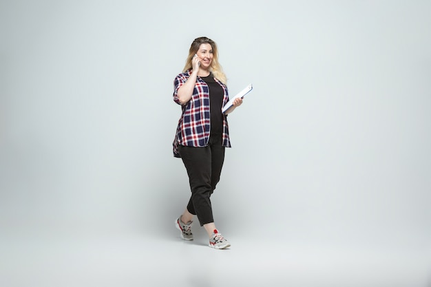 Free photo young caucasian woman in casual wear on gray wall