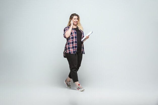 Young caucasian woman in casual wear on gray wall