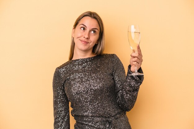 Young caucasian woman celebrating new year isolated on yellow background dreaming of achieving goals and purposes