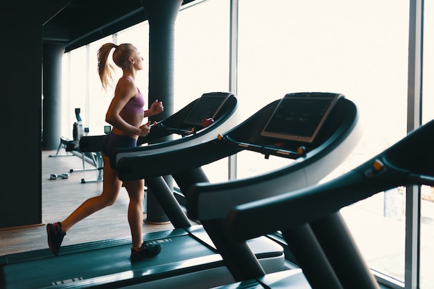Young caucasian woman doing exercise with dumbbells while training arms at the gym