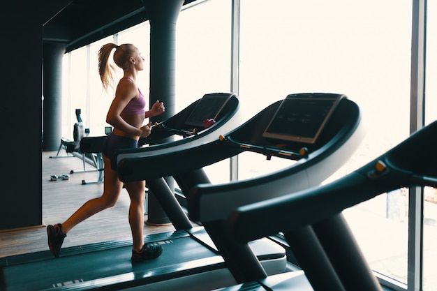 Free photo young caucasian woman doing exercise with dumbbells while training arms at the gym