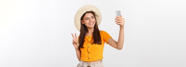 白い背景の夏の旅行 co に分離された自分自身と selfie を楽しんでいる若い白人女性