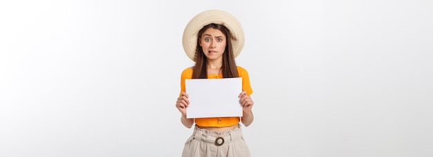 Young caucasian woman holding blank paper sheet over isolated background scared in shock with a surp
