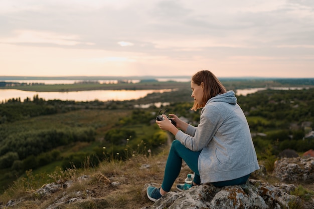 Young Caucasian woman navigating a flying drone with remote control