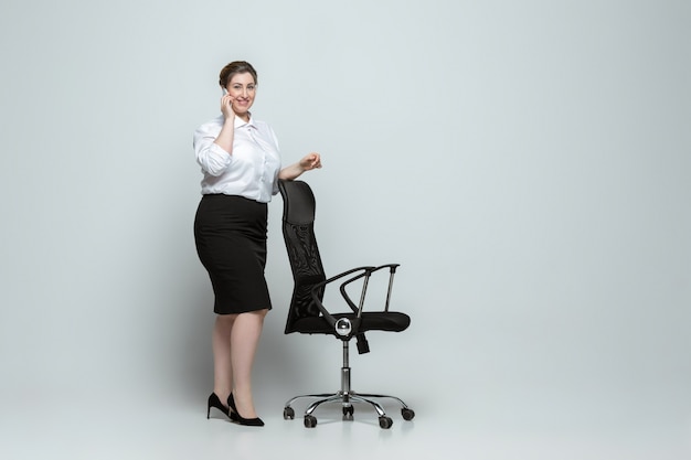 Young caucasian woman in office attire on gray wall