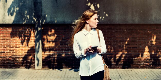 屋外で携帯電話を使用して立っている若い白人の女性
