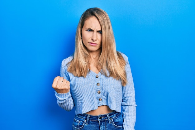 Free photo young caucasian woman wearing casual clothes angry and mad raising fist frustrated and furious while shouting with anger. rage and aggressive concept.