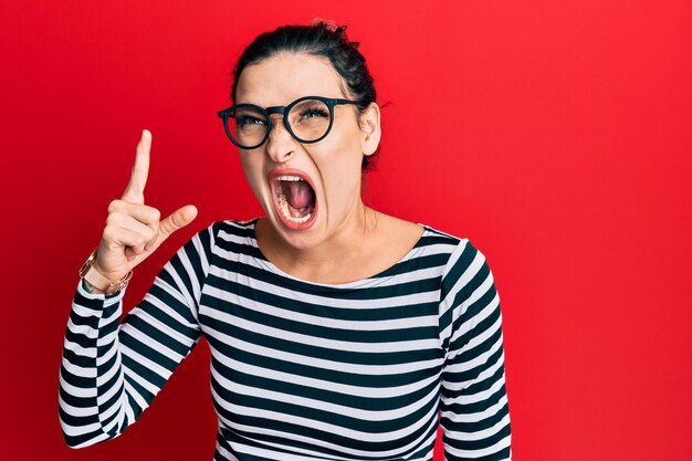 Young caucasian woman wearing casual clothes and glasses pointing finger up with successful idea exited and happy number one