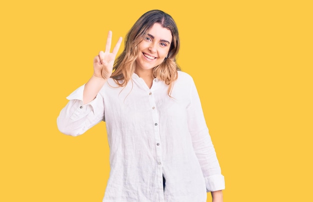 Young caucasian woman wearing casual clothes showing and pointing up with fingers number two while smiling confident and happy