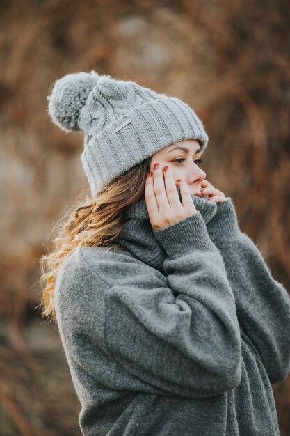 Молодая кавказская женщина в сером свитере и зимней шапке - зимняя концепция