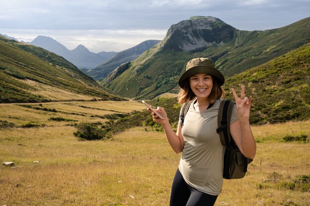 Молодая кавказская женщина в шляпе и рюкзаке делает забавные жесты