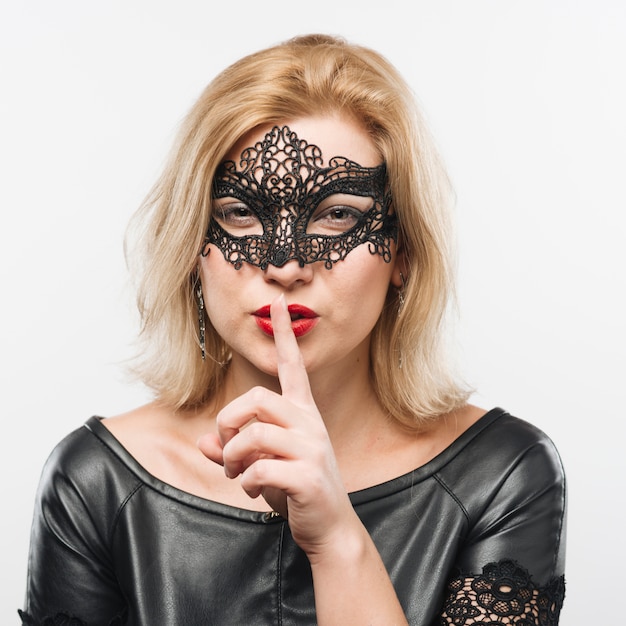 Young charming blond lady in mask with finger near lips 