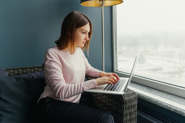 Young charming female freelancer using laptop computer for distance job 