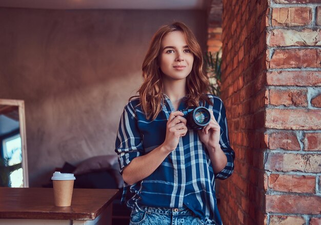 Young charming girl photographer stands in a room with a loft in