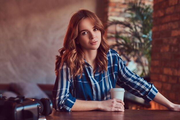 A young charming sensual girl photographer drinks a morning coff