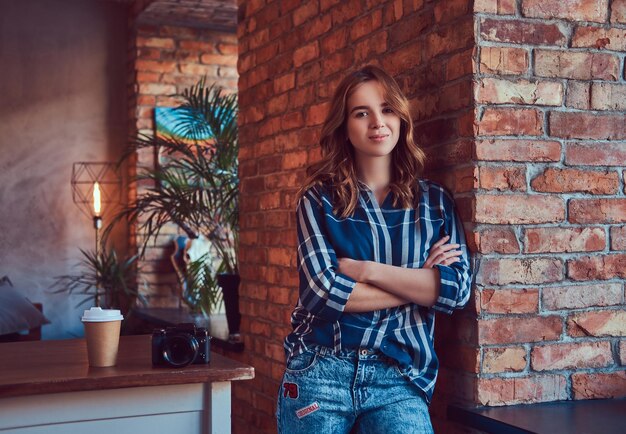 A young charming sensual girl stands leaning against a brick wal