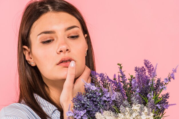 Young charming woman holding bunch of flowers near face