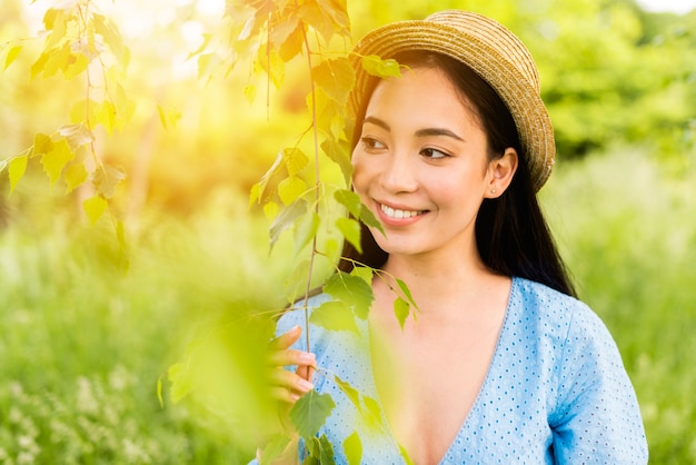 Молодая очаровательная женщина улыбается, прислонившись к листьям в природе