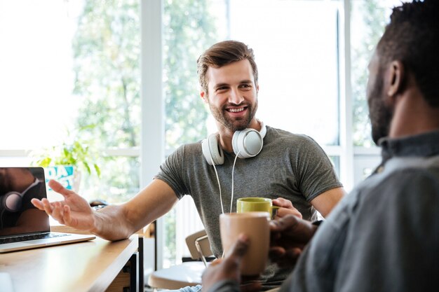 オフィスのコワーキングに座っている若い陽気な同僚