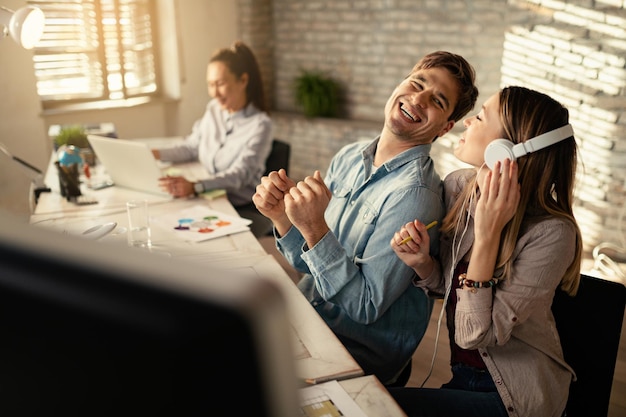 Foto gratuita giovani imprenditori allegri che si divertono mentre lavorano insieme in ufficio