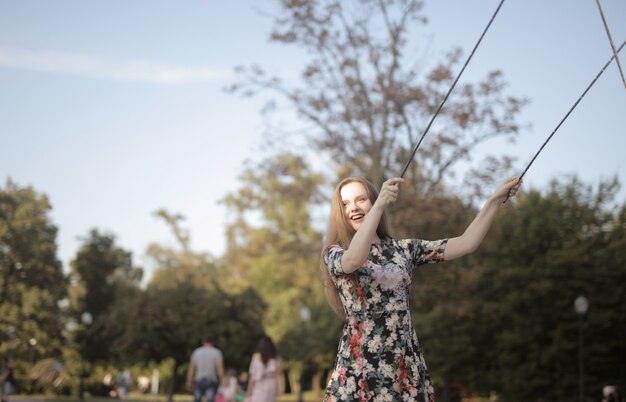 日光の下で公園で若い陽気な女性