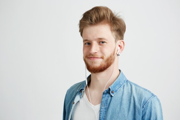 Young cheerful guy in headphones smiling listening to streaming music.