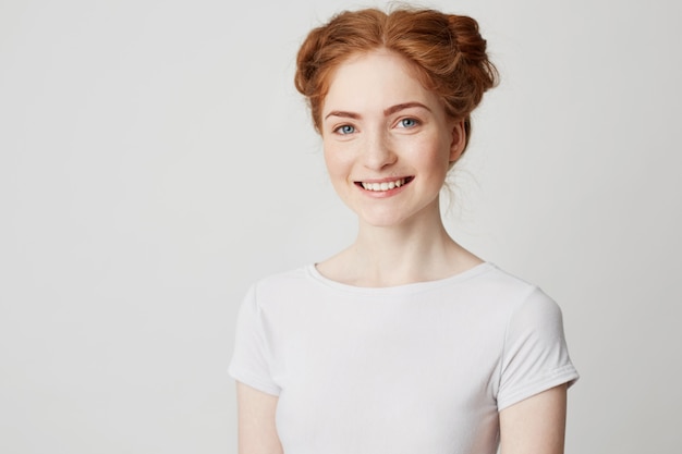 Free photo young cheerful happy ginger girl with buns and freckles smiling .