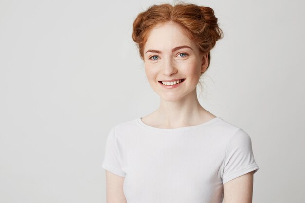 Young cheerful happy ginger girl with buns and freckles smiling .