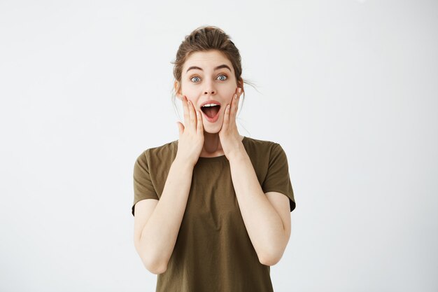 Young cheerful happy woman rejoicing smiling with hands on cheeks.